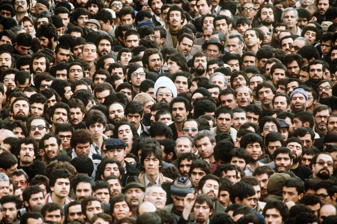 A crowd in Tehran walks down a street in February 1979, several days after Ayatollah Khomeini returned from exile. As the uprising gripped the city, protesters wore a shroud or white ribbon around the heads to signify their willingness to die as martyrs. (AFP Photo)