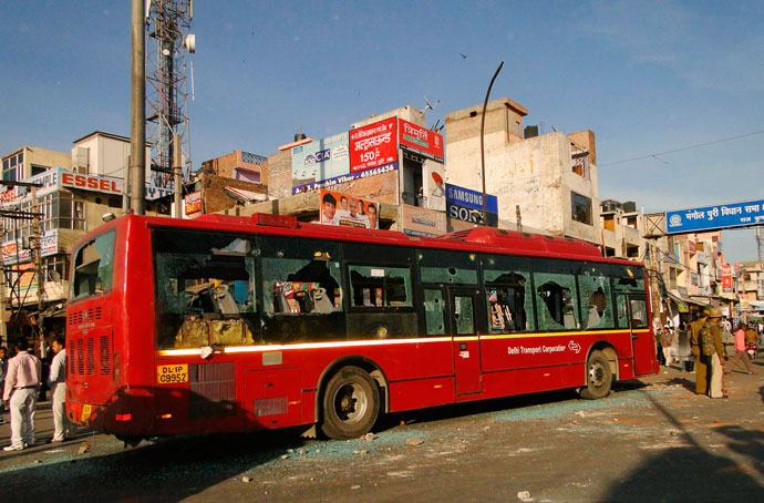 People stand next to a bus that was damaged by the demonstrators during a protest in New Delhi March 1, 2013.(Reuters / Stringer)