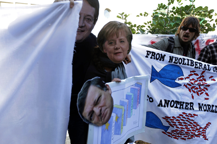 Cypriots holding cut-out masks of German Chancellor Angela Merkel, European Commission head Jose Manuel Barroso and Cypriot President Nicos Anastasiades take part in a protest against an EU bailout deal outside the parliament in Nicosia on March 18, 2013. (AFP Photo / Patrick Baz)