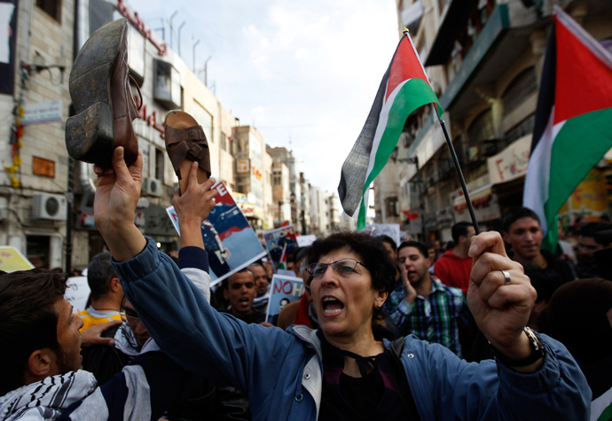 Palestinian demonstrators hold shoes and flags as they take part in a protest in the West Bank city of Ramallah March 19, 2013 (Reuters / Ammar Awad)
