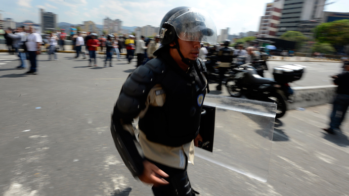 A riot police officer runs in downtown Caracas on March 21, 2013 during a demonstration of opposition students demanding to the National Electoral Council (CNE) transparency during the presidential elections next February 14 (AFP Photo / Juan Barreto)