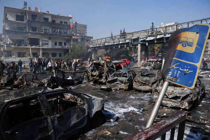 People walk near debris and damaged vehicles after an explosion at central Damascus February 21, 2013.(Reuters / Sana)