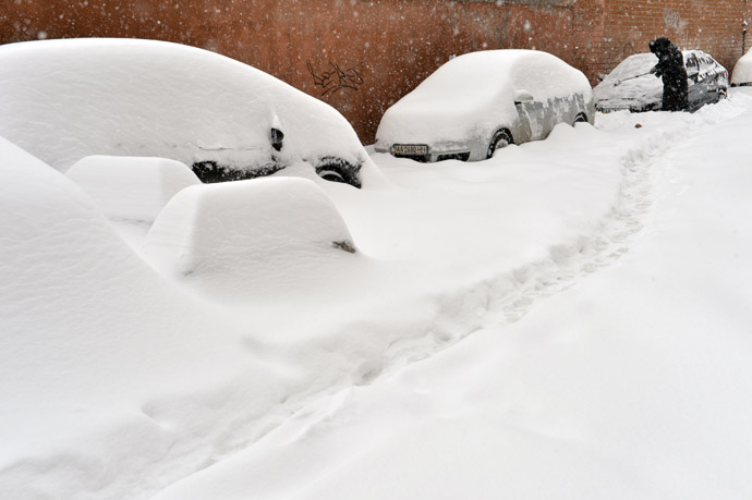 A woman removes snow from her car during a storm in the Ukraine capital Kiev on March 23, 2013. (AFP Photo)