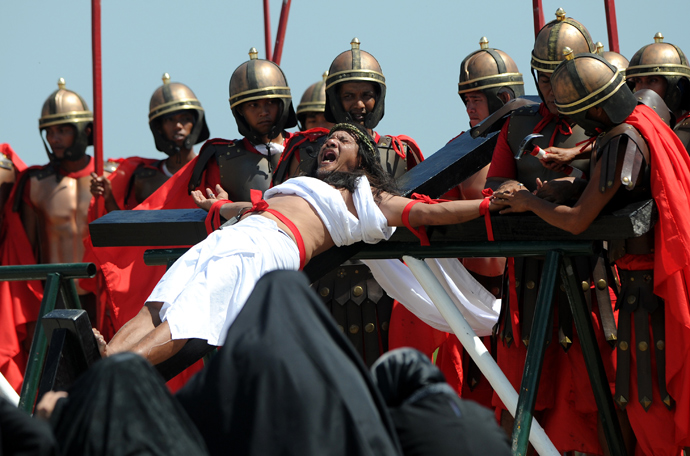 Philippine Christian devotee Ruben Enaje (C), grimaces in pain as he is nailed to the Cross by men dressed as Roman soldiers during a re-enactment of the crucifixion of Jesus Christ on Good Friday in San Fernando City, Pampanga province, north of Manila on March 29, 2013 (AFP Photo / Noel Celis)