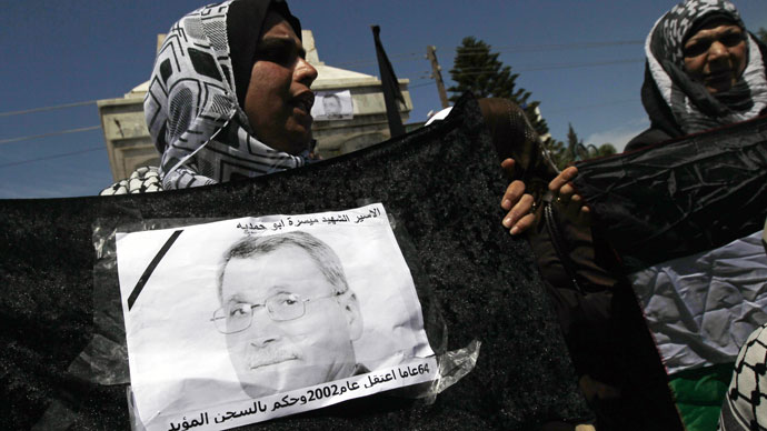 A Palestinian woman holds a picture of Maisara Abu Hamdiyeh, an Israeli-held prisoner who died of cancer while in detention, during a protest against his death in Gaza City on April 2, 2013.(AFP Photo / Mohammed Abed)