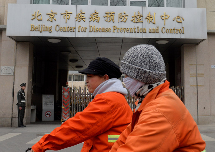 Two women ride past the Beijing Center for Disease Prevention and Control after the arrival there of testing kits for the H7N9 bird flu virus in Beijing on April 4, 2013. (AFP Photo/Mark Ralston)