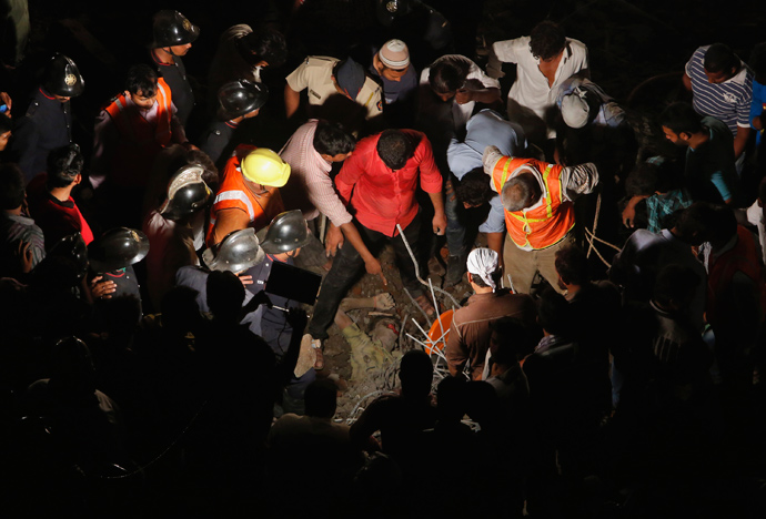 Rescue workers gather around the body of a man who was trapped under rubble at the site of a collapsed residential building in Thane, on the outskirts of Mumbai April 4, 2013 (Reuters / Vivek Prakash)