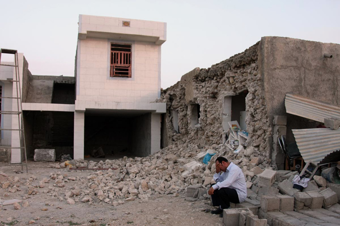 An Iranian man squats next to his destroyed house in the town of Shonbeh, southeast of Bushehr, on April 9, 2013 after a powerful earthquake struck near the Gulf port city of Bushehr. (AFP Photo / Mohammad Fatemi)