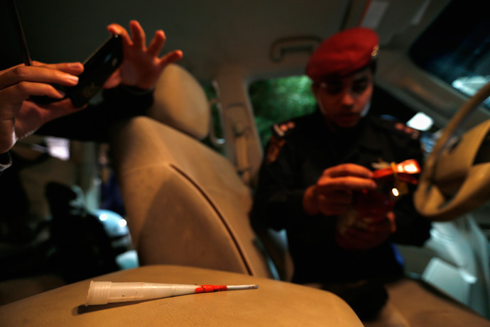 A journalist (L) takes a photo of a home-made dart used by protesters as a riot police officer prepares for his patrol in the area of Budaiya, west of Manama, April 11, 2013 (Reuters / Hamad I Mohammed)