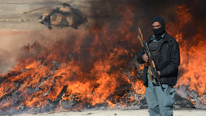 This photo taken on December 19, 2012 shows an Afghan policeman standing guard as a pile of narcotics is burned by officials on the outskirts of Jalalabad Nangarhar province. (AFP Photo / Shan Marai)