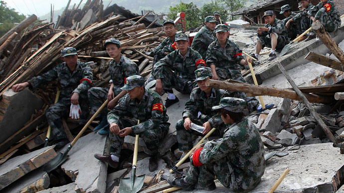 Rescuers sit on ruins of a house in Longmen township, an area very close to the epicenter of a shallow earthquake at magnitude 7.0 that hit the city of Ya'an, southwest China's Sichuan province on April 20, 2013.(AFP Photo / China OUT)