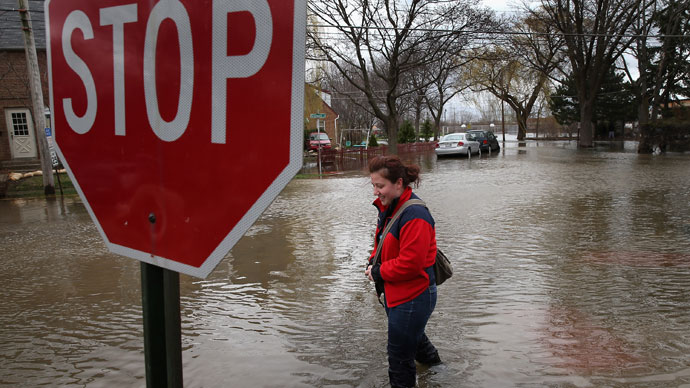 A woman walks down a flooded sidewalk on April 19, 2013 in Des Plaines, Illinois.(AFP Photo / Scott Olson)