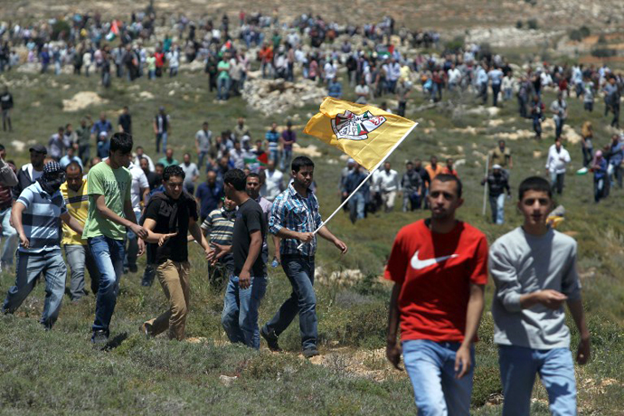 A Palestinian demonstrator from the West Bank village of Deir Jarir waves the Fatah movement flag as he marches with fellow protestors against construction on their land by members of the nearby Jewish settlement of Ofra on April 26, 2013. (AFP Photo / Abbas Momani)