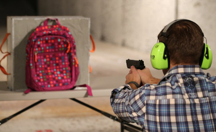  Chief Operating Officer for Amendment II, Rich Brand, shoots a child's backpack with their Rynohide CNT Shield in it. (AFP Photo / George Frey)