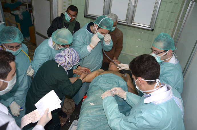 In this image made available by the Syrian News Agency on March 19, 2013, medics and other masked people attend to a man at a hospital in Khan al-Assal in the northern Aleppo province, as Syria's government accused rebel forces of using chemical weapons for the first time. The opposition denied the claim, saying instead that government forces might have used banned weapons. (AFP Photo / SANA)
