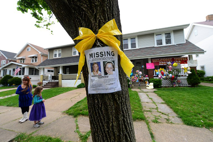 A missing person sign displaying portraits of Amanda Berry , one of the three women held captive for a decade, stands in front of her sister's house May 7, 2013 in Cleveland. (AFP Photo / Emmanuel Dunand)