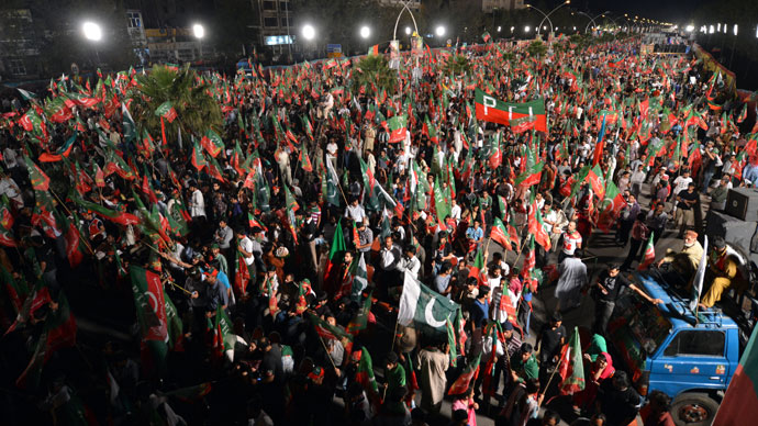Supporters of Pakistani politician and former cricketer Imran Khan wave party flags as they wait to listen Khan video link address from a hospital during last election campaign meeting in Islamabad on May 9, 2013.(AFP Photo / Aamir Qureshi)