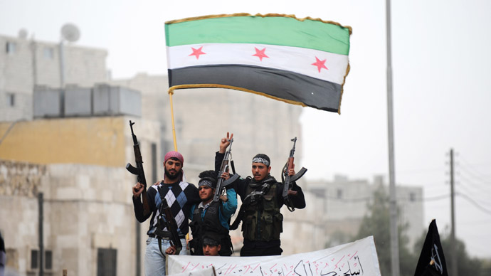 Syrian rebels raise their weapons under a pre-Baath Syrian flag currently used by the opposition during an anti-regime protest in the northern city of Aleppo on March 22, 2013. (AFP Photo)