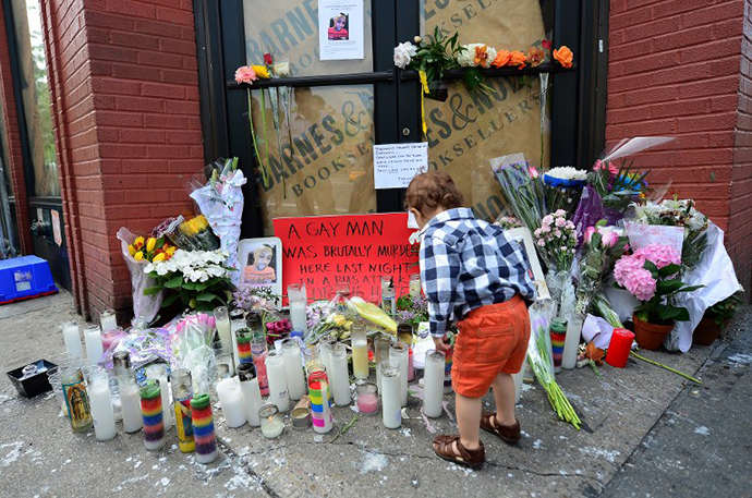 A young boy offers flowers at a makeshift shrine set on the location where Mark Carson, 32, a gay man, was shot dead in what police are calling a hate crime in Greenwich Village in New York, May 20, 2013. (AFP Photo / Emmanuel Dunand)
