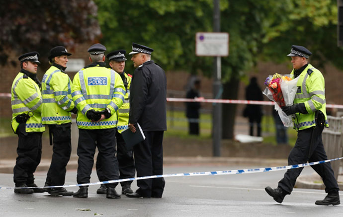 A police officer carries flowers near the scene of the killing of a British soldier in Woolwich, southeast London May 23, 2013.(Reuters / Luke MacGregor)