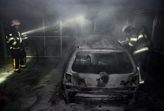 Firemen extinguish a burning car parked in an indoor garage in the Stockholm suburb of Tureberg after youths rioted in several different suburbs for a fourth consecutive night on May 24, 2013 (AFP Photo / Jonathan Nackstrand)