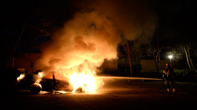 Firemen extinguish a burning car in Kista after youths rioted in few differant suburbs around Stockholm on May 21, 2013.(AFP Photo / Jonathan Nackstrand)