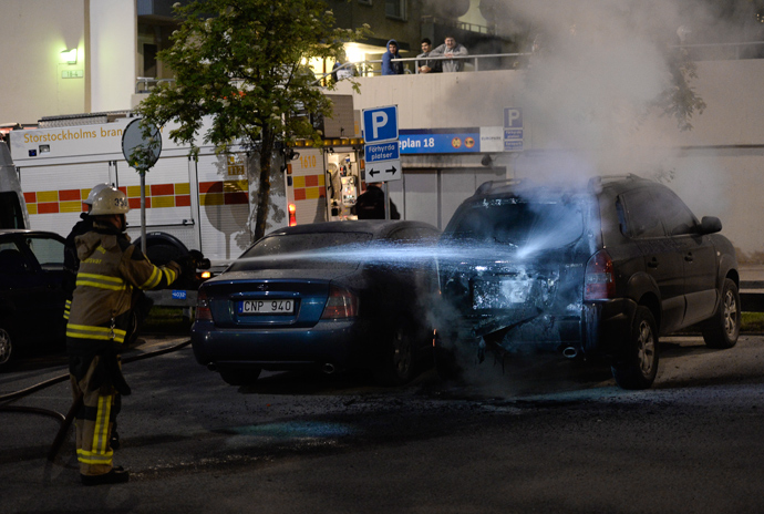 Firemen extinguish a burning car in the Stockholm suburb of Tensta after youths rioted in few different suburbs around Stockholm and Sweden on May 24, 2013 (AFP Photo)