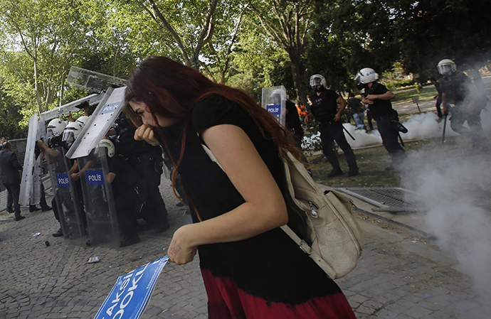 A demonstrator covers her face as riot police use tear gas to disperse the crowd during a protest against the destruction of trees in a park brought about by a pedestrian project, in Taksim Square in central Istanbul May 31, 2013. (Reuters / Murad Sezer)