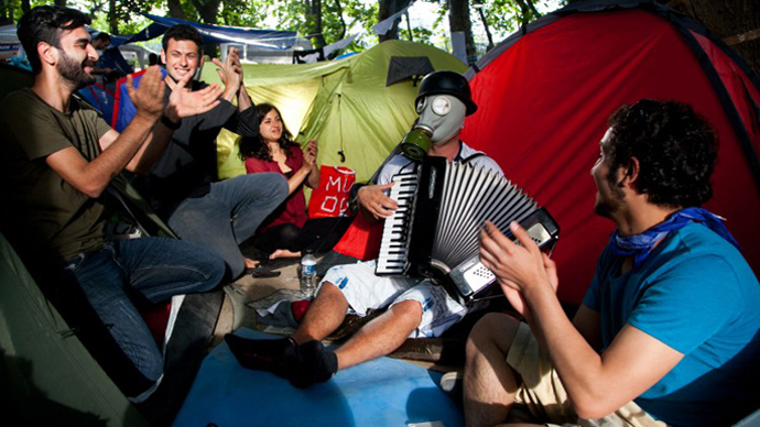 A demonstrator wearing a gas mask plays the accordeon as he sits with others near a tent at a makeshipt camp on Taksim square in Istanbul on June 7, 2013. (AFP Photo / Gurcan Ozturk)