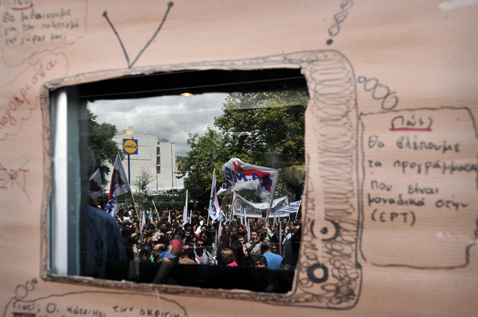 Protesters are reflected on glass inside a carboard-made TV screen at the entrance of the Greek television broadcasting company ERT headquarters in Athens, during a 24-hour strike to support ERT employees and state television on June 13, 2013 (AFP Photo / Louisa Gouliamaki)