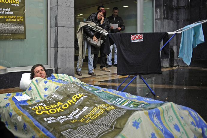 A man lies on a camping mat installed in front of a Basque government's unemployment service "Lanbide" on May 22, 2013 in the Northern Spanish Basque town of Barakaldo. (AFP Photo / Rafa Rivas)