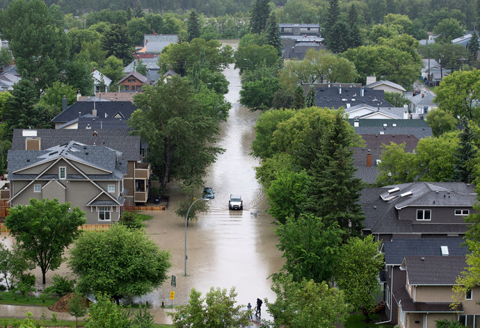 A vehicle drives down a flooded street in the neighbourhood of Sunnyside in Calgary, Alberta June 21, 2013 (Reuters / Todd Korol)