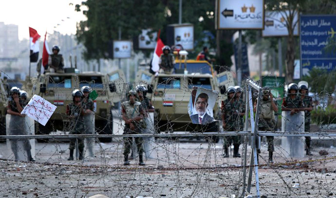 A poster of deposed president Mohamed Morsi hangs on barbed wire that blocks the access to the headquarters of the Republican Guard in Cairo on July 9, 2013. (AFP Photo / Mahmud Hams)