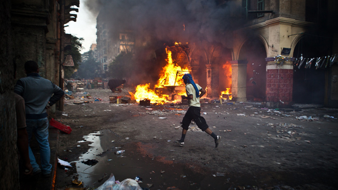 A supporter of the Muslim Brotherhood and of ousted president Mohamed Morsi runs past a burning vehicle during clashes with security officers close to Cairo's Ramses Square, on August 16, 2013 (AFP Photo)