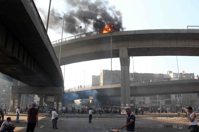 Egyptian Muslim brotherhood supporters of Egypt's ousted president Mohamed Morsi look up at a vehicle burning on six October bridge during clashes with riot police after security forces dispersed Morsi supporters on August 14, 2013 in Cairo. (AFP Photo/Khaled Kamel)