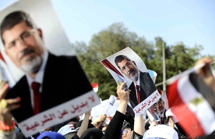  Supporters of Islamist Egyptian President Mohamed Morsi holds up his image during a rally outside Cairo University on June 2, 2013. (AFP Photo / Mohamed El-Shahed)