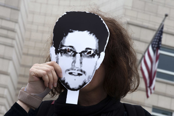 A woman holds a portrait of former U.S. spy agency contractor Edward Snowden in front of her face as she stands in front of the U.S. embassy during a protest in Berlin, July 4, 2013. (Reuters/Thomas Peter)