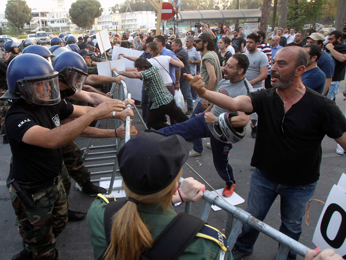 Demonstrators scuffle with the police after lawmakers by majority vote approved an EU bailout, outside the parliament in the Cypriot capital of Nicosia (Reuters / Andreas Manolis)