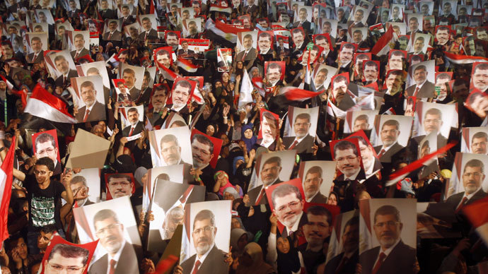 Members of the Muslim Brotherhood and supporters of Egypt's President Mohamed Mursi hold pictures of him as they react after the Egyptian army's statement was read out on state TV, at the Raba El-Adwyia mosque square in Cairo July 3, 2013.(Reuters / Khaled Abdullah)
