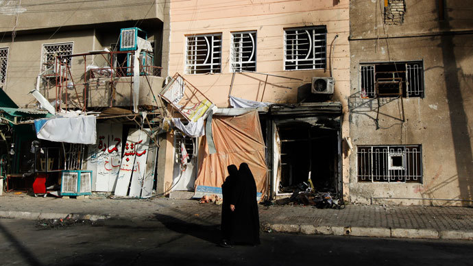 Women walk past the site of a car bomb attack at the neighbourhood of Tobchi in Baghdad, July 21, 2013. (Reuters / Thaier al-Sudani)