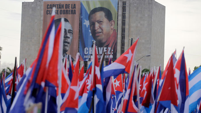 People carry flags near a poster of late Venezuelan leader Hugo Chavez during the Mayday parade in Havana's Revolution Square May 1, 2013.(Reuters / Desmond Boylan)