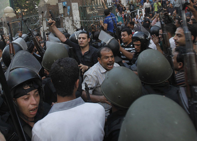 A plain clothes policeman (upper left) points his gun as security forces escort Muslim Brotherhood members through supporters of the interim government installed by the army from the al-Fath mosque on Ramses Square in Cairo August 17, 2013. (Reuters/Amr Abdallah Dalsh)