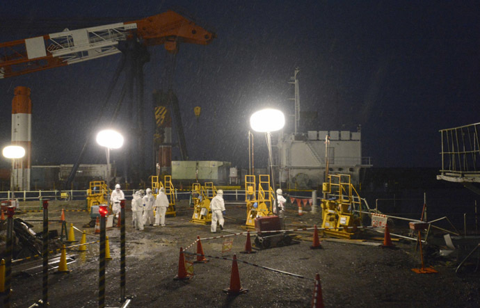 Workers wearing protective suits and masks operate a soil improvement work site of the shore barrier to stop radioactive water from leaking into the sea, near the No.1 and No.2 reactor buildings of the tsunami-crippled Fukushima Daiichi nuclear power plant in Fukushima, in this photo released by Kyodo July 22, 2013. (Reuters/Kyodo)