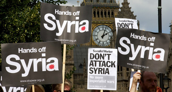 Demonstrators hold up placards during a protest against potential British military involvement in Syria at a gathering outside the Houses of Parliament in central London on August 29, 2013. (AFP Photo / Andrew Cowie)
