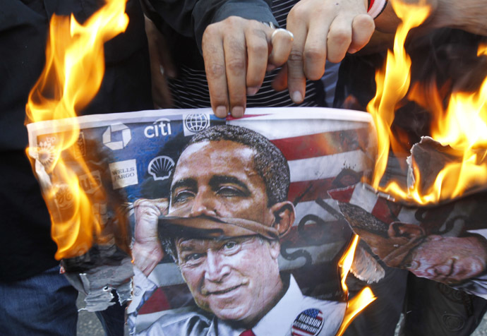 protester holds a poster burning on which is depicted former US president George W. Bush taking off a mask of current President Barack Obama during a demonstration of supporters of Syrian regime near the US embassy, east of Beirut against a possible US military strike on Syria on September 7, 2013. (AFP Photo)