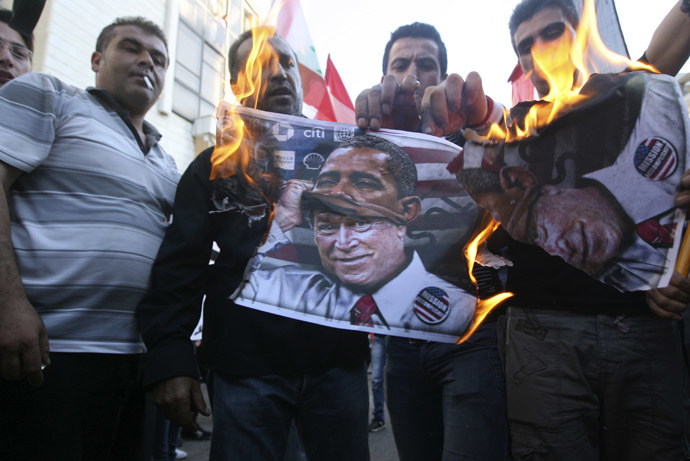Activists burn a poster depicting former U.S President George Bush disguised as current U.S President Barack Obama during a protest against potential U.S. strikes on Syria, near the U.S. embassy in Awkar, north of Beirut, September 7, 2013. (Reuters/Hasan Shaaban)