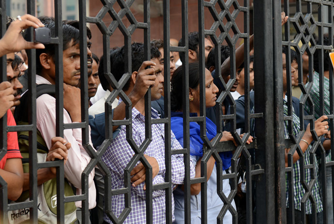 An Indian woman stands among a group of men inside the gate of the Saket district court in New Delhi on September 13, 2013, as they watch members of the media interview a lawyer for one of the convicted men in a rape case. (AFP Photo/Roberto Schmidt)