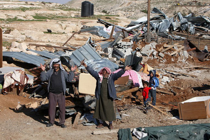 (FILE photo) Palestinian Bedouin men react amidst the rubble of a structure after it was razed by the Israeli army in the West Bank village of Zayem, near Jerusalem (AFP Photo / Ahmad Gharabli)
