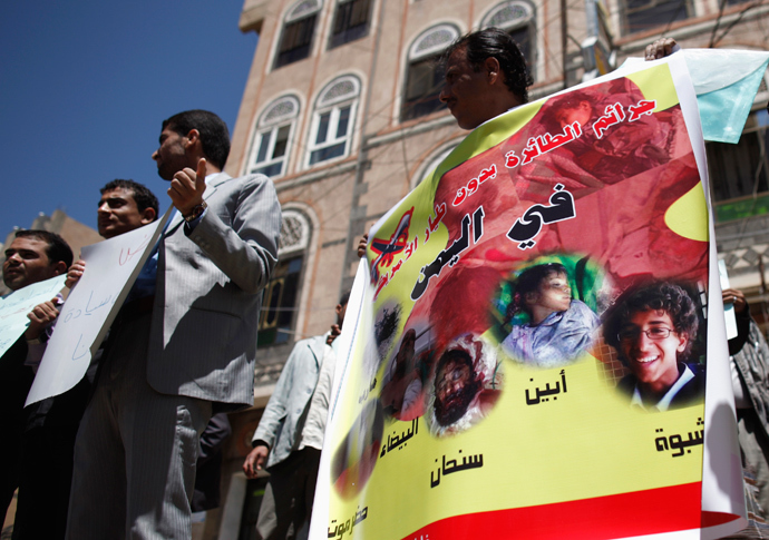 An activist holds a banner with photos of people killed in drone attacks, during a protest against the U.S. drone strikes in Yemen outside the U.S. embassy in Sanaa April 29, 2013 (Reuters / Khaled Abdullah)
