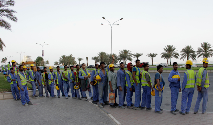 Foreign workers wait for their bus at a construction site in Doha, Qatar (Reuters / Fadi Al-Assaad)